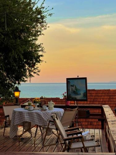 a table and chairs on a deck with a view of the ocean at VELAMUNDi INN Batu Ferringhi in Batu Ferringhi
