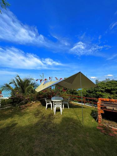a table and chairs under an umbrella in the grass at VELAMUNDi INN Batu Ferringhi in Batu Ferringhi