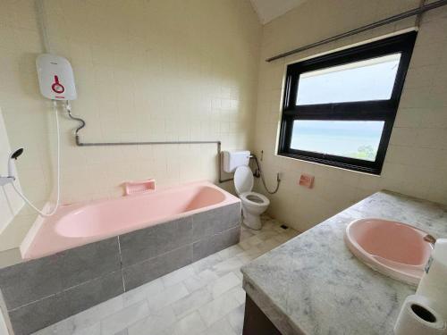 a bathroom with a pink bath tub and a toilet at VELAMUNDi INN Batu Ferringhi in Batu Ferringhi