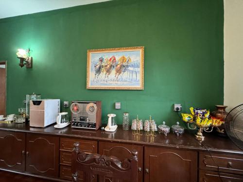 a green wall with a wooden dresser in a room at VELAMUNDi INN Batu Ferringhi in Batu Ferringhi