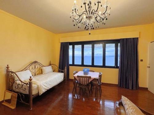 a bedroom with a bed and a table and a chandelier at VELAMUNDi INN Batu Ferringhi in Batu Ferringhi