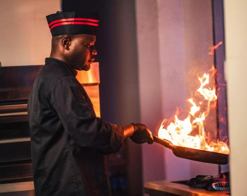 a man holding a pan with fire in it at The Cove Apartments in Abuja