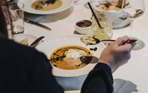 a person sitting at a table with a bowl of food at Wein Erlebnis Hotel Maimühle in Perl