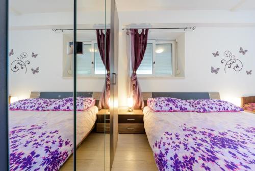 a bedroom with two beds and a glass wall at Apartments Milić in Mlini