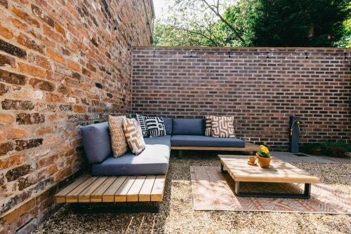 a patio with couches and a table and a brick wall at Host & Stay - Bracken Cottage in Stokesley