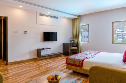 a hotel room with a bed and a tv at Spectrum Resort, Spa & Residences in Udaipur