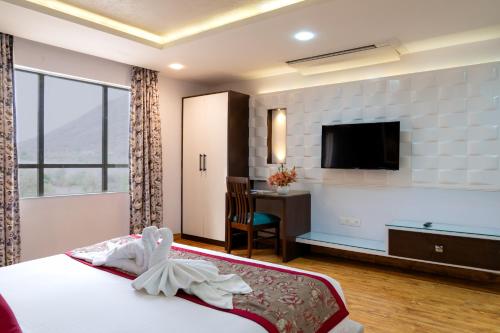 a hotel room with a bed and a flat screen tv at Spectrum Resort, Spa & Residences in Udaipur
