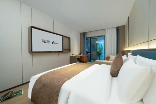 a bedroom with a white bed and a flat screen tv at Yizhi Hotel - Guangzhou Shamian Island Huangsha Metro Station-Canton Fair free shuttle bus included Breakfast in Guangzhou