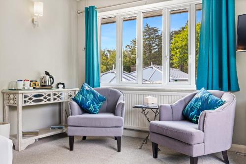 a living room with two chairs and a window at Rooms at David Lloyd Wickwoods in Albourne