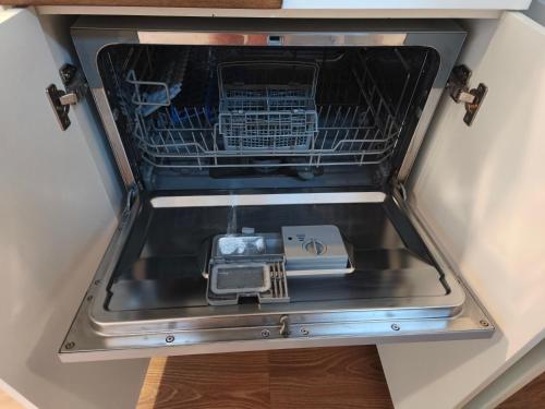 an open dishwasher with a plate in the bottom drawer at City TinyHouse under WaterTower in Wrocław