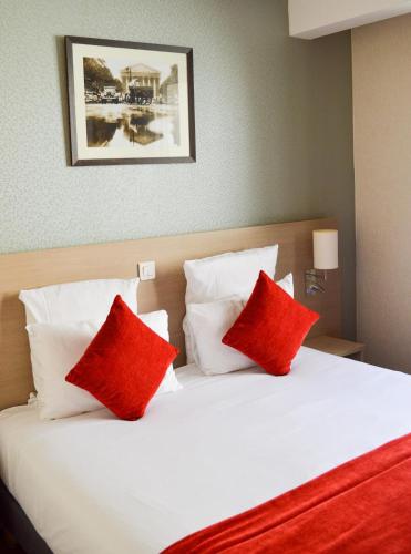 a bedroom with a bed with red and white pillows at Dièse Hôtel Bastille in Paris