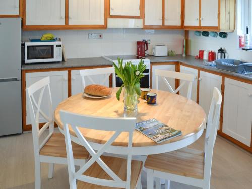 - une cuisine avec une table en bois et des chaises blanches dans l'établissement Cobi's Cape Cottage, à Saint Just