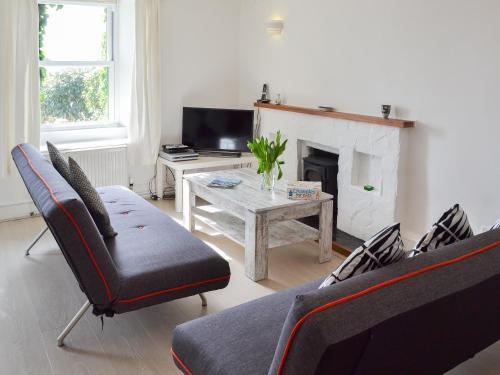 - un salon avec un canapé et une table avec une cheminée dans l'établissement Cobi's Cape Cottage, à Saint Just