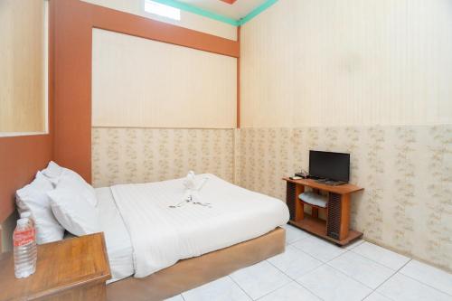 a bedroom with a white bed and a television at SAHABAT Hotel Tangerang By Reccoma in Kampungbaru