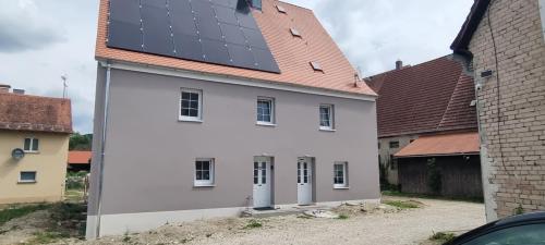a white house with solar panels on its roof at gemütliche Ferienwohnung Achteltal in Simmelsdorf