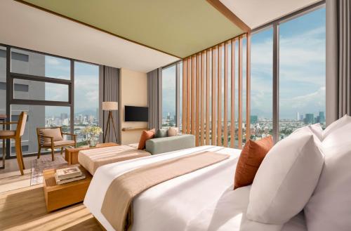 a bedroom with a large bed and a large window at Signature by M Village Beachfront Hotel in Da Nang