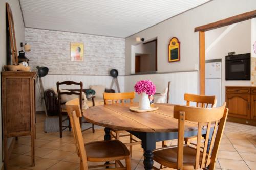 une cuisine et une salle à manger avec une table et des chaises en bois dans l'établissement Gîte la Chapotière proche du Puy du Fou, à La Verrie