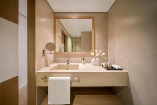 a bathroom with a sink and a mirror at Signature by M Village Beachfront Hotel in Da Nang