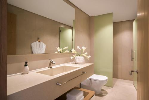 a bathroom with a sink and a toilet and a mirror at Signature by M Village Beachfront Hotel in Da Nang