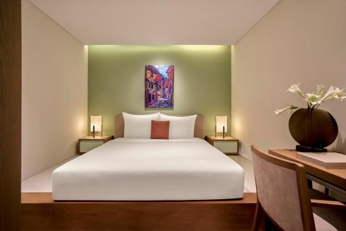 a bedroom with a white bed and a painting on the wall at Signature by M Village Beachfront Hotel in Da Nang