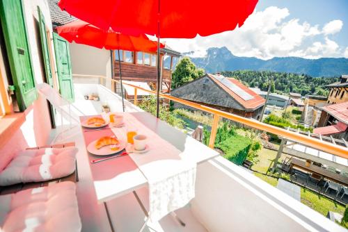 a balcony with a table and a red umbrella at Villa en plein cœur de Leysin in Leysin