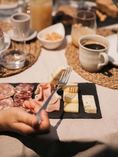 a table with a person holding a knife and fork and cheese at Villaggio Brambui Durando in Portacomaro