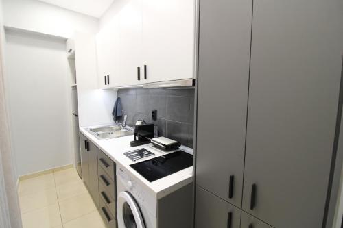 a small kitchen with white cabinets and a stove at G&E Kavala Apartments in Kavala