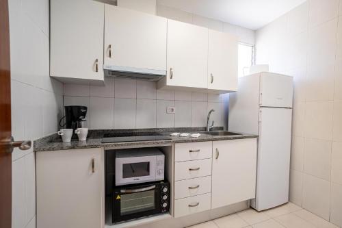 a kitchen with white cabinets and a microwave and a refrigerator at ED. MISTRAL VIDABER in Oropesa del Mar