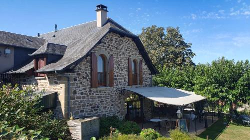 a stone house with a white tent in the yard at Gîte Bellevue - Domaine de la chapelle en Corrèze in La Chapelle-aux-Brocs