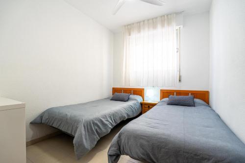 two beds in a small room with a window at ED. MISTRAL VIDABER in Oropesa del Mar