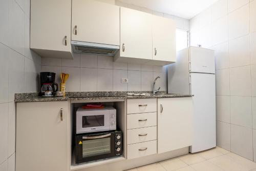 a white kitchen with white cabinets and a microwave at ED. MISTRAL VIDABER in Oropesa del Mar