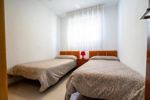 two beds in a small room with a window at ED. MISTRAL VIDABER in Oropesa del Mar