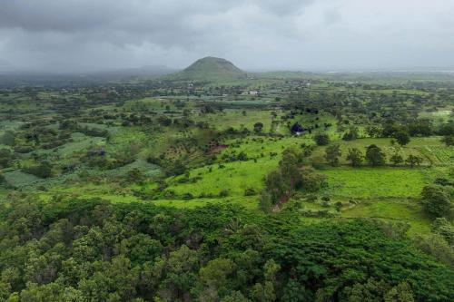 an aerial view of a green field with a mountain at StayVista's Lush Villa - Rustic-Meets-Modern Interiors, Pool, Jacuzzi & Indoor activities in Wādhiware