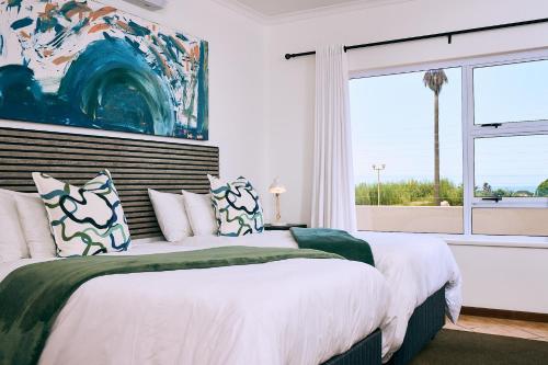two beds in a bedroom with a large window at Ocean House Swakopmund in Swakopmund