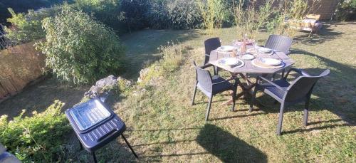 a table with chairs and a grill in a yard at Le Birdie - Maison & Jardin à proximité de Chantilly in Vineuil-Saint-Firmin