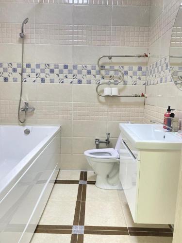een badkamer met een bad, een toilet en een wastafel bij 2комн Барыс Арена in Astana