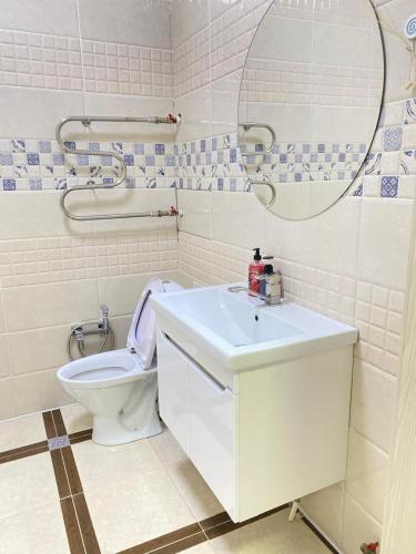 een badkamer met een toilet, een wastafel en een spiegel bij 2комн Барыс Арена in Astana