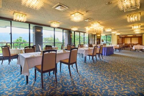 a dining room with tables and chairs and windows at Hotel Marroad Hakone in Hakone