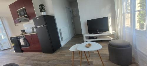 a living room with a refrigerator and a table and a tv at Le Birdie - Maison & Jardin à proximité de Chantilly in Vineuil-Saint-Firmin