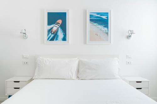 a bedroom with a white bed with two pictures on the wall at Puolo Seaside Apartment 3 in Massa Lubrense