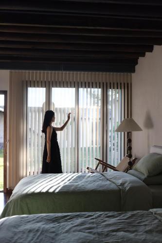 a woman standing in a bedroom looking out the window at Dali Healing Yard 喜洲禾隐星登 in Dali