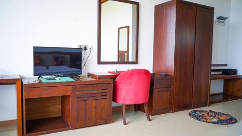 a room with a desk with a red chair and a television at La Casablanca Tourist Hotel Negombo in Negombo