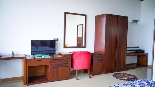 a bedroom with a desk with a red chair and a mirror at La Casablanca Tourist Hotel Negombo in Negombo
