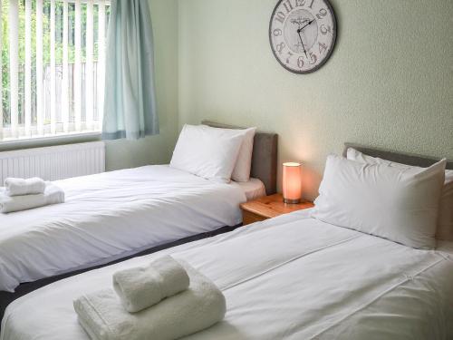 two beds in a room with a clock on the wall at Jenny's in Stalham
