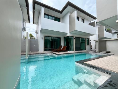 a swimming pool in front of a house at Bay Sand Villa by Jai House Phuket in Ban Klang