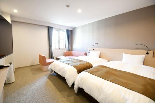 a hotel room with two beds and a couch at Hotel Marroad Hakone in Hakone