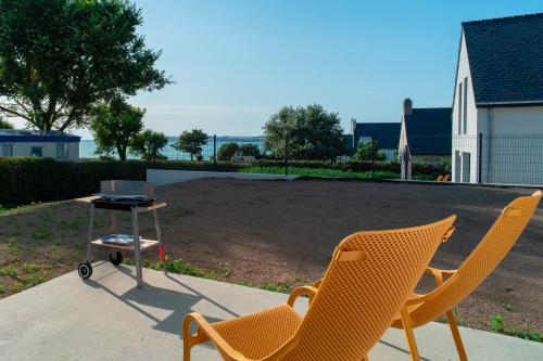 two chairs and a table with a grill in a yard at Maison EG - Presqu'ile de Crozon in Plomodiern