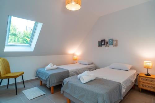 two beds in a room with a window and a chair at Maison EG - Presqu'ile de Crozon in Plomodiern