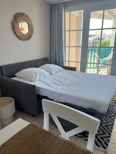 ein Schlafzimmer mit einem Bett, einem Spiegel und einem Fenster in der Unterkunft Fleurs du lac studio 2 adultes et 2 enfants avec terrasse vue sur le lac et accès parc aquatique gratuit in Talmont