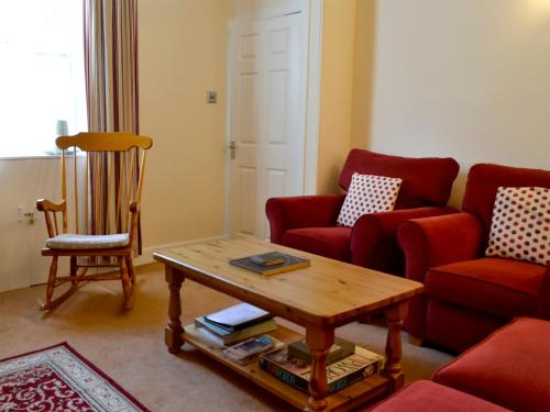 a living room with red chairs and a coffee table at Kirsty Cottage in Moffat
